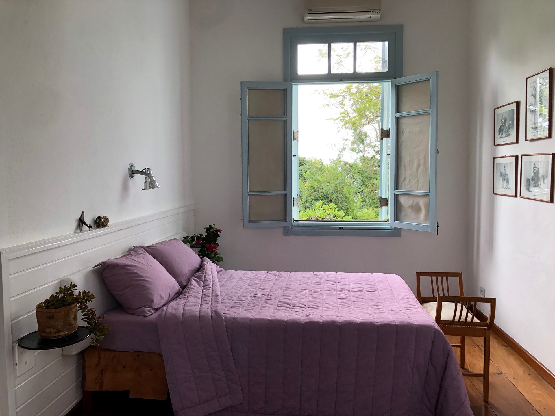 Bedroom with red bedding and open window showing greenery