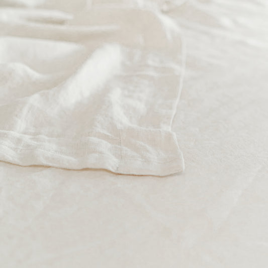 A beige linen flat sheet on a bed, with pillowcases displayed in front.
