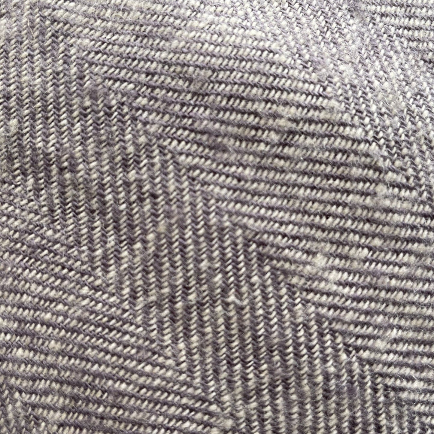 Linen herringbone throw in soft gray tones, showcasing a textured pattern with diagonal lines and subtle variations.