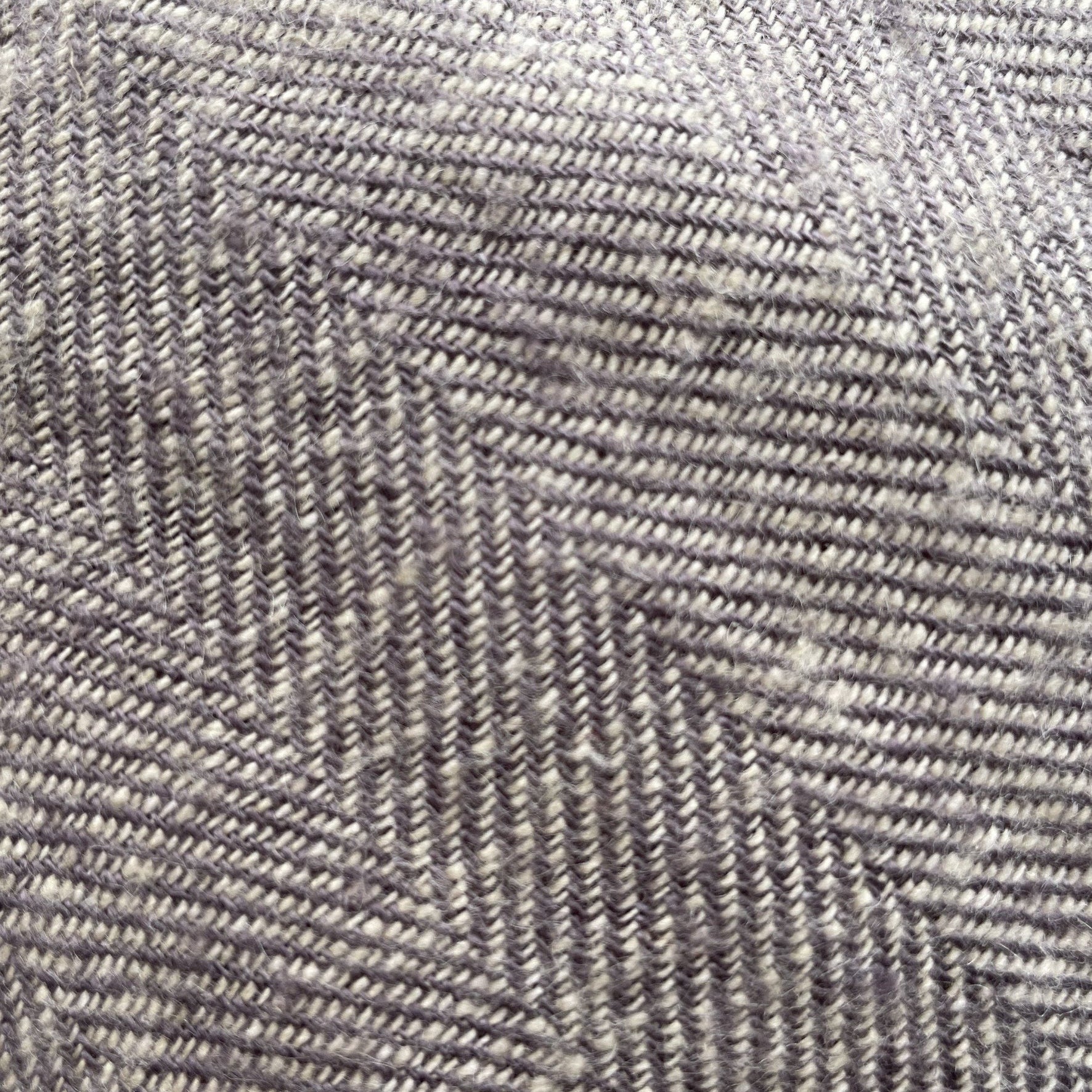 Linen herringbone throw in soft gray tones, showcasing a textured pattern with diagonal lines and subtle variations.