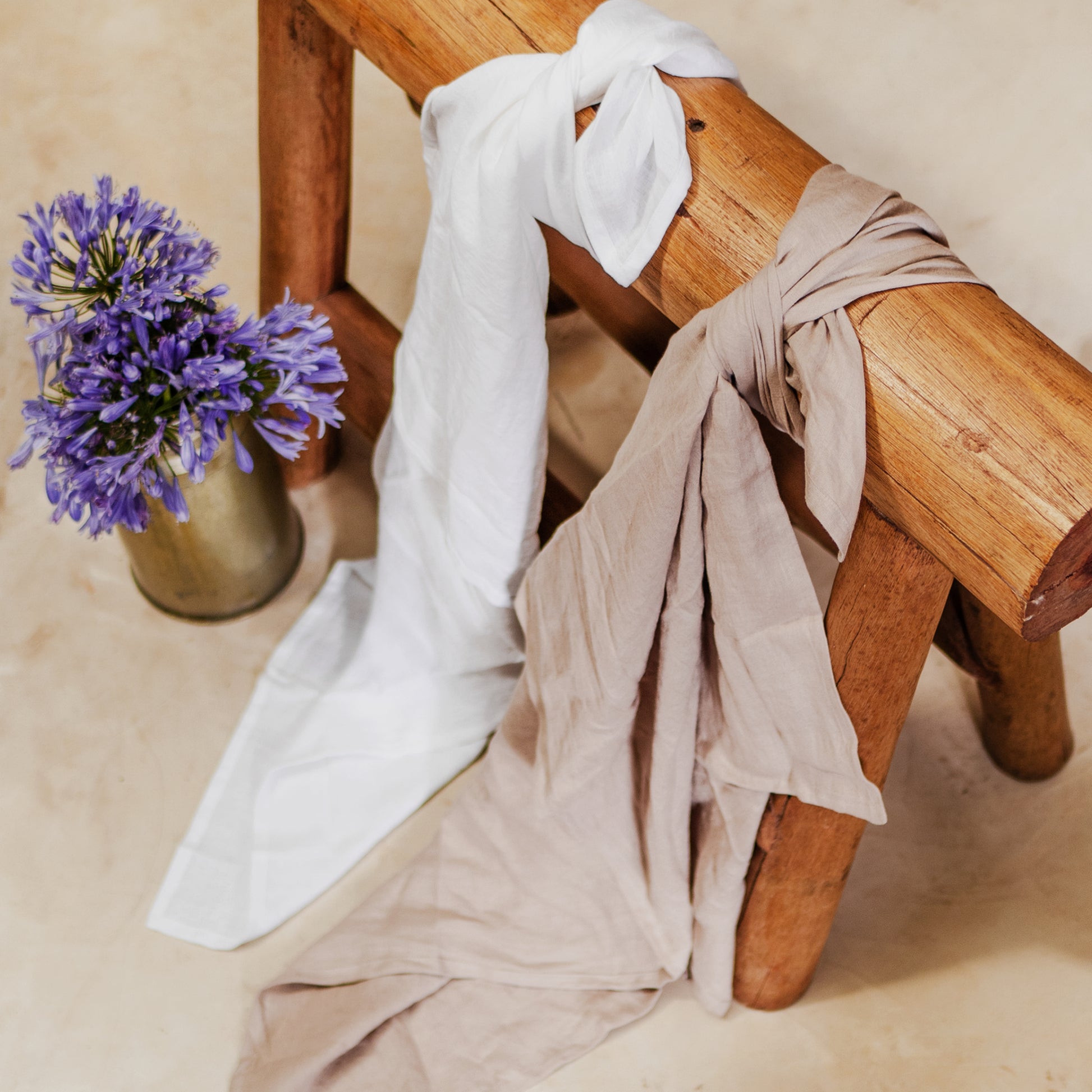 two linen swaddle, khaki and white, wrapped around wooden base